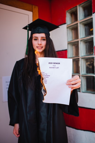 woman in black academic dress holding white printer paper